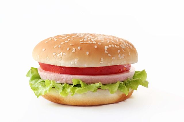 Hamburger na białym tle z wystającą sałatą 